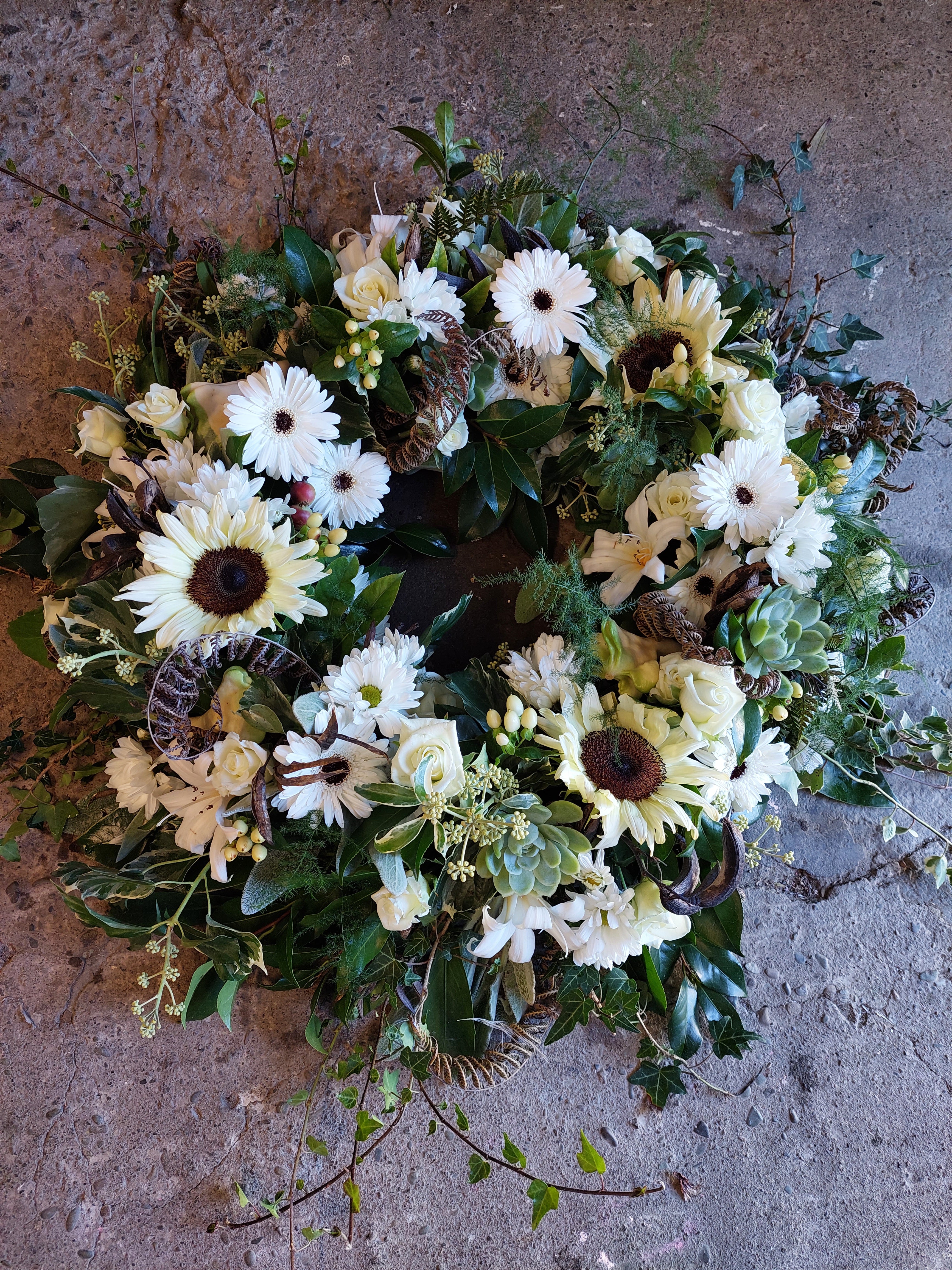 Wreath of Remembrance for funerals and memorials made with soft yellow and white flowers and lush foliage.