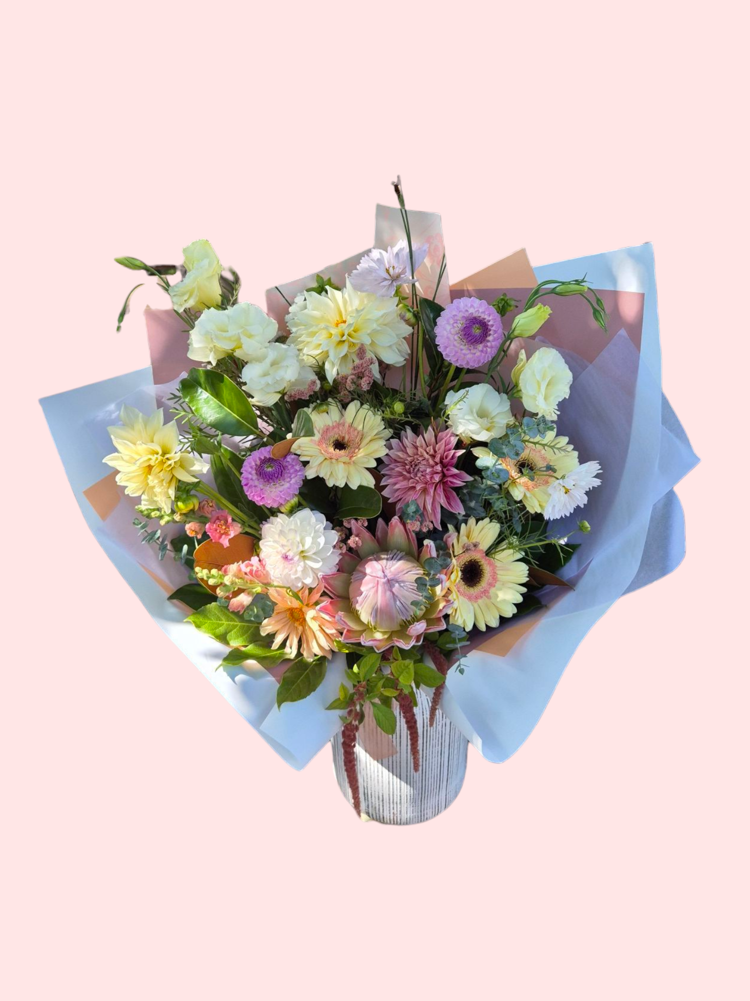 Pastel-Licious floral bouquet made with pink, peach and white flowers, wrapped in matching tissue paper.