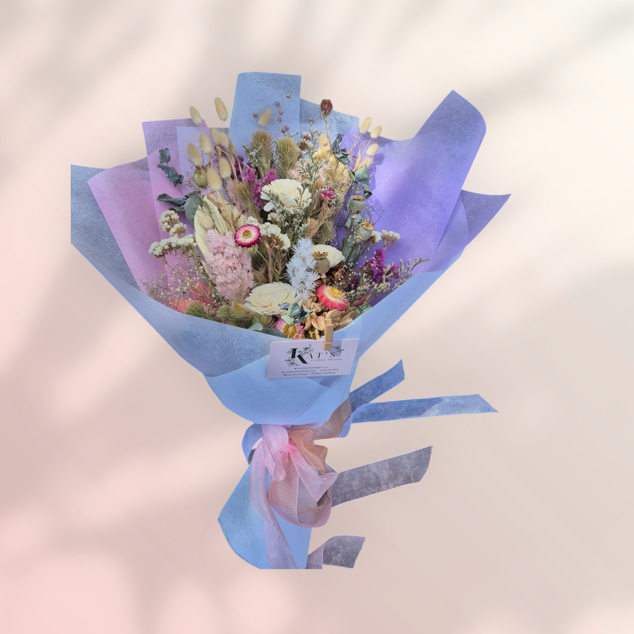 Blush & Bloom dried floral bouquet, made with pink and white flowers and neutral foliage, wrapped in pink and white tissue paper.