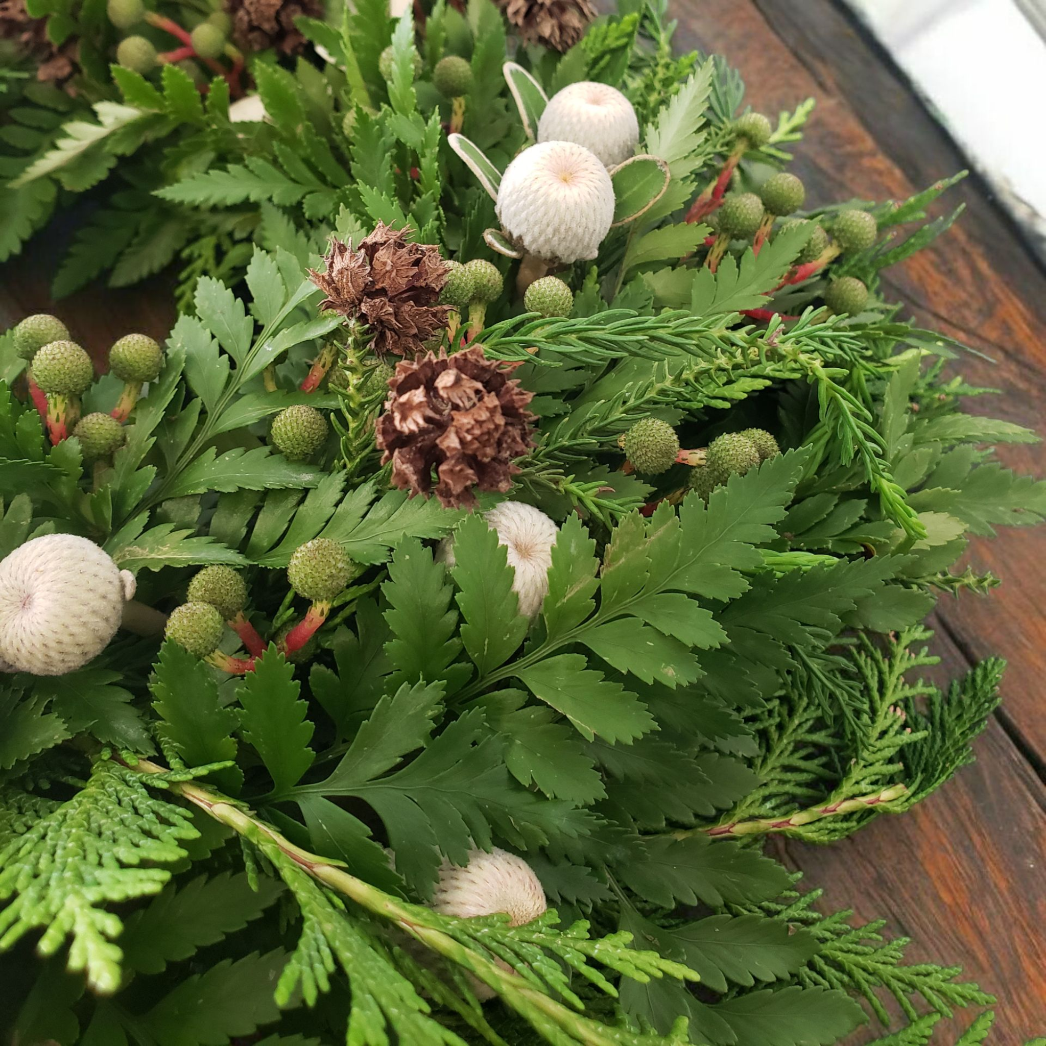 Christmas Greenery Wreath made with pine and other foliage, with added festive white, red and green flowers.