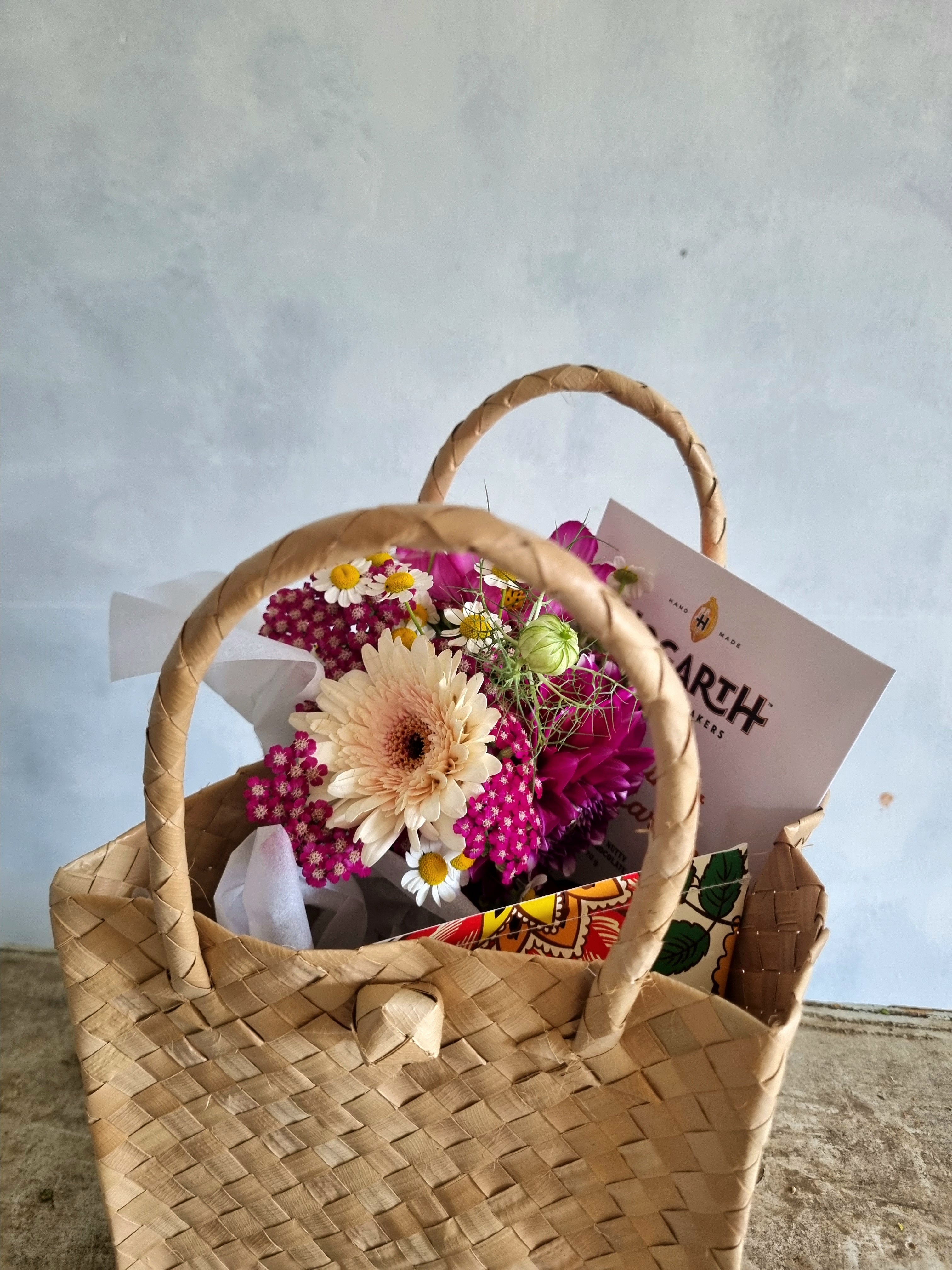 Thinking of You Kete with a pink and white floral posie, Botanical Bath Bomb and bar of Hogarth Chocolate presented in a woven Māori kete (basket).