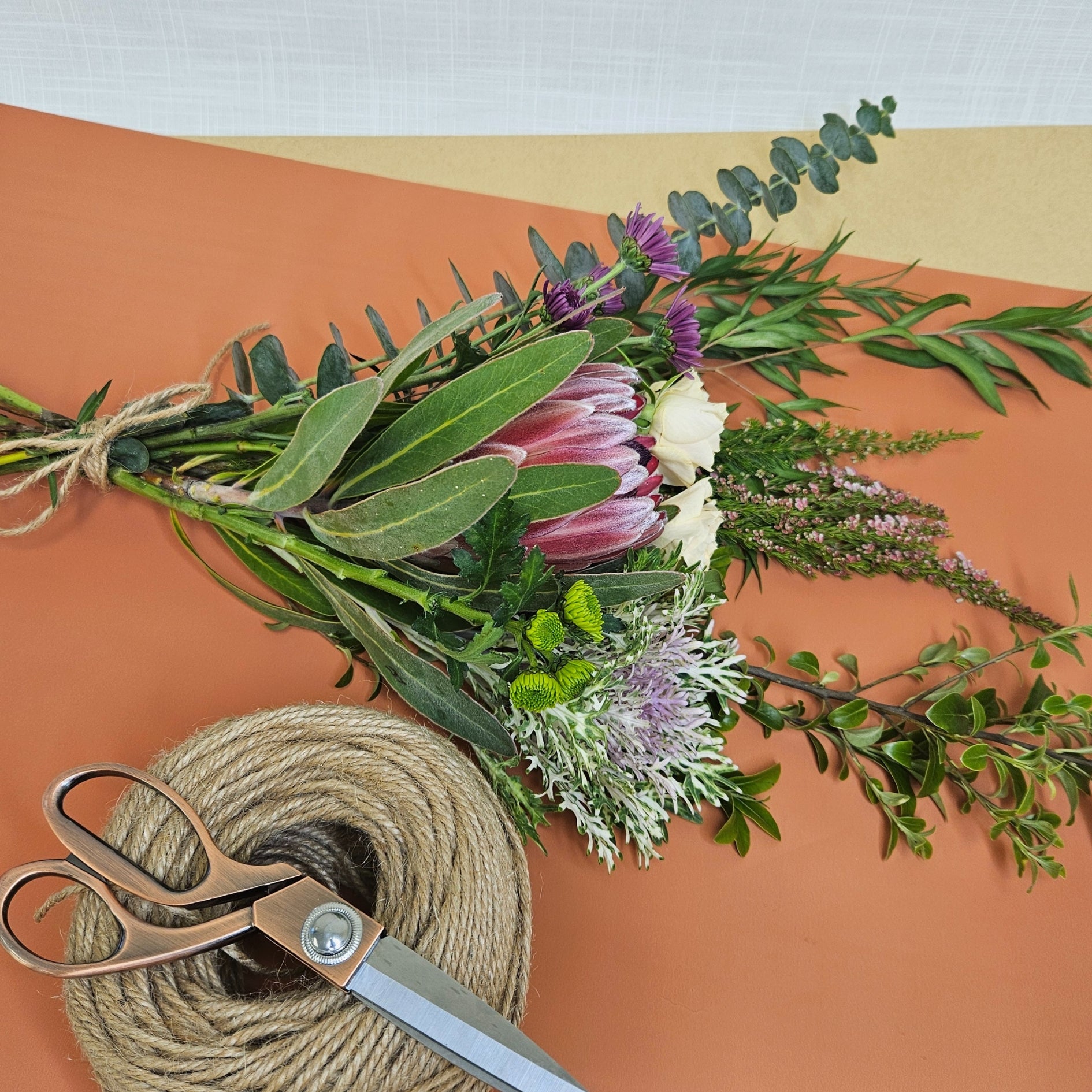 A bundle of fresh flowers and greenery ready for arranging, with scissors and twine.