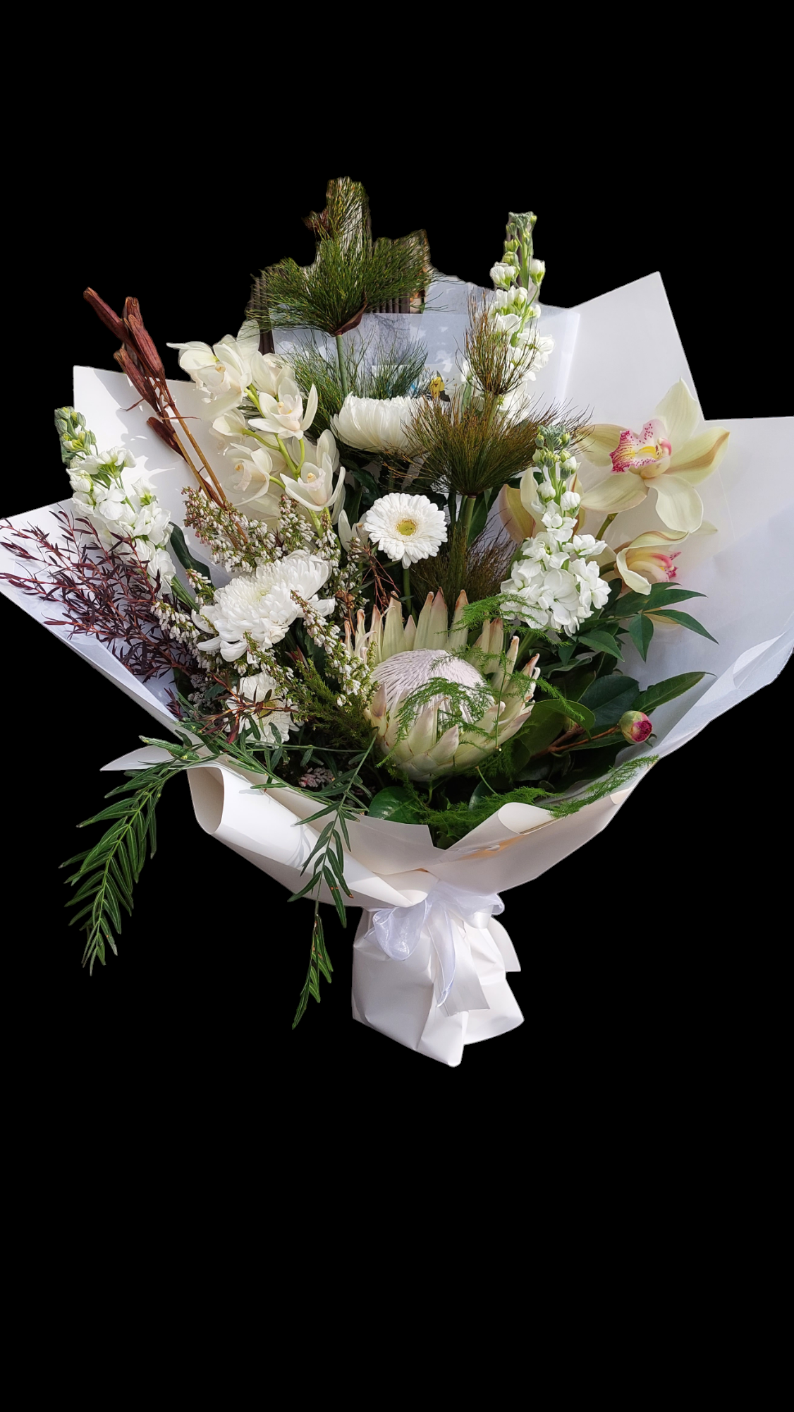 Ivory Whites floral bouquet made with a variety of white and cream flowers and green foliage, wrapped in matching tissue paper.