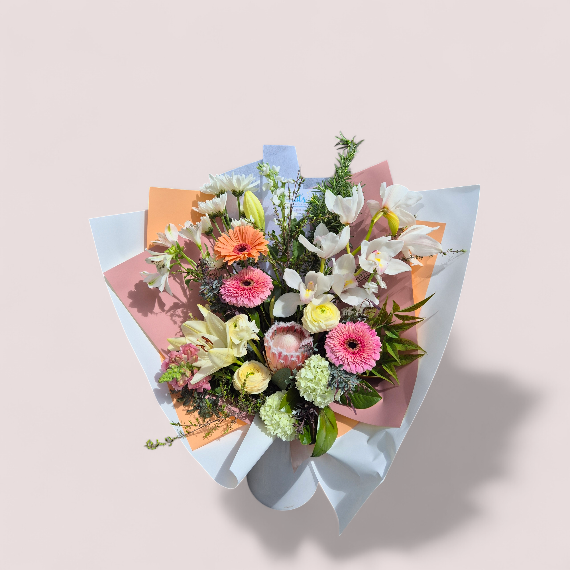 Seasonal Large Bouquet - Florist Choice with white , pink and yellow flowers wrapped in pink, white and orange tissue paper.