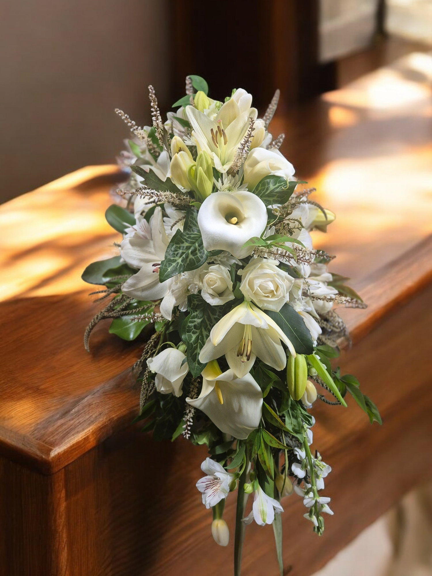 White Casket Spray for funerals and memorials made with an assortment of white flowers and soft green foliage.