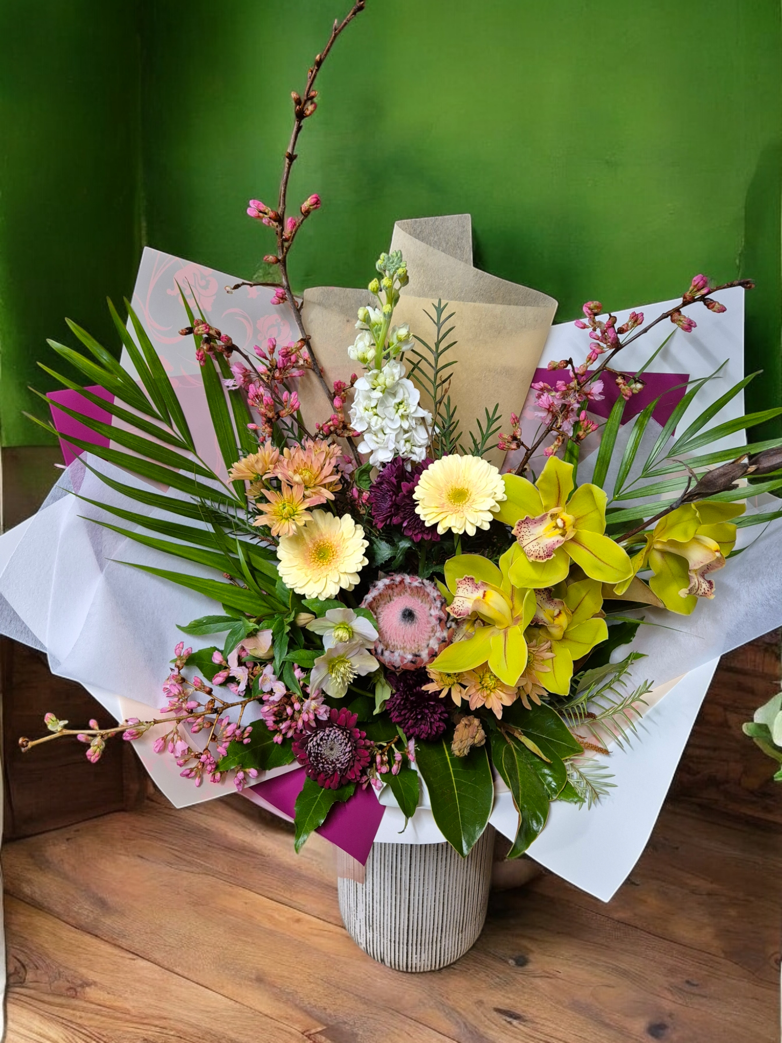 Seasonal Large Bouquet - Florist Choice with pink and yellow flowers wrapped in pink and white tissue paper.