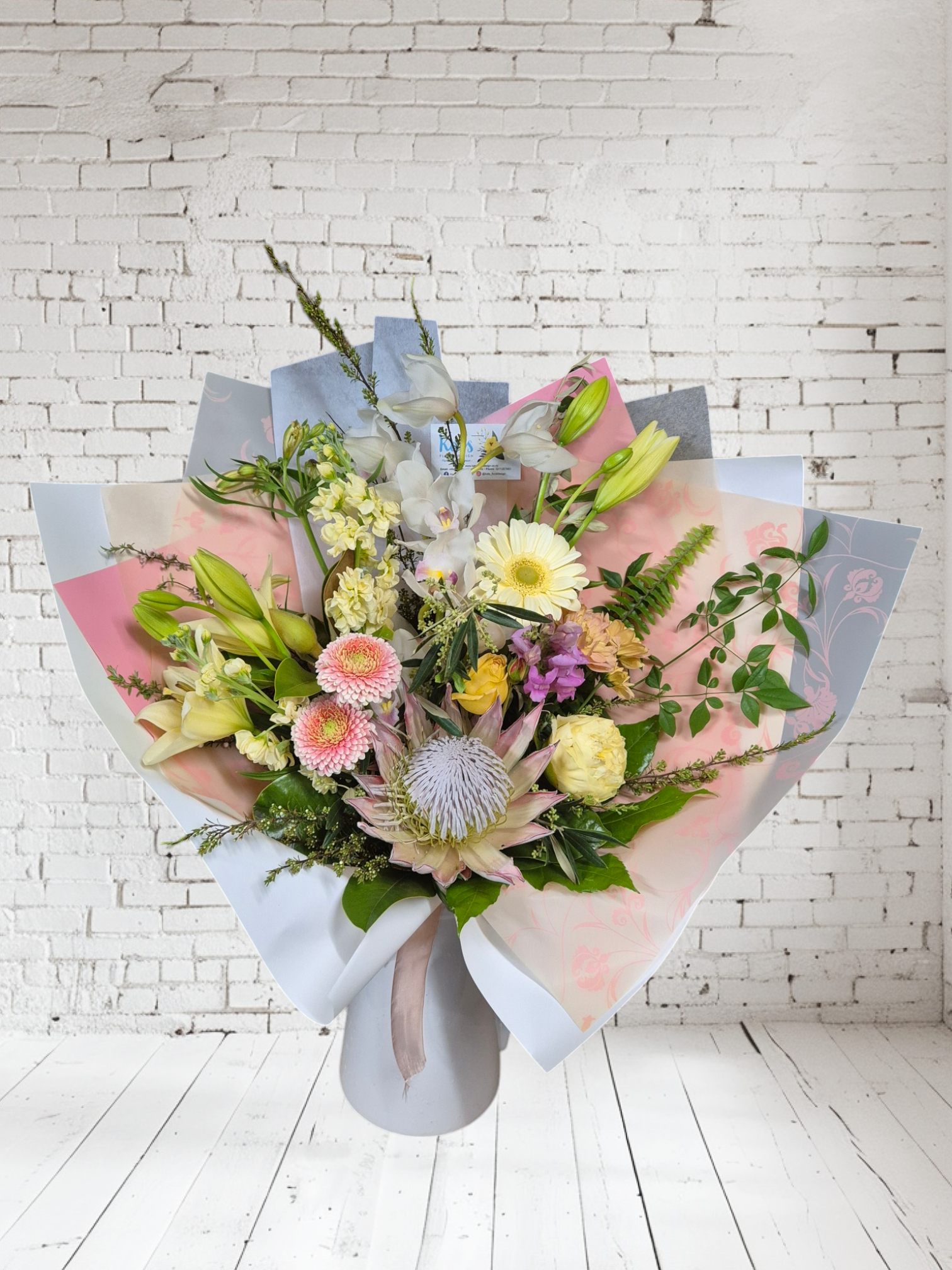 Pastel-Licious floral bouquet made with pink, peach and white flowers, wrapped in matching tissue paper.