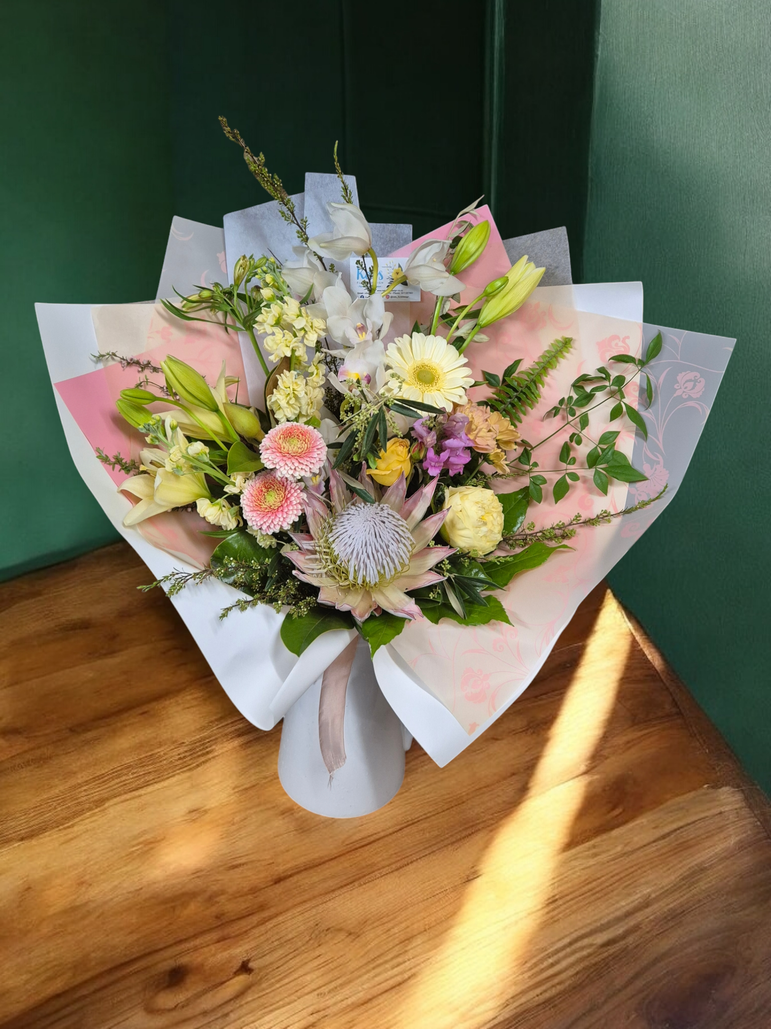 Seasonal Large Bouquet - Florist Choice with pink and yellow flowers wrapped in pink and white tissue paper.