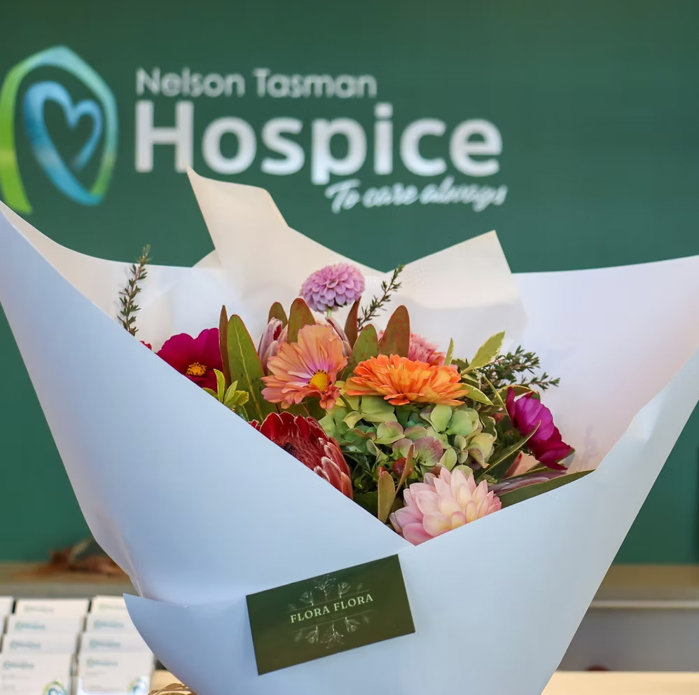 Protea Bouquet made with proteas and complimentary flowers in a variety of colours, wrapped in white paper.
