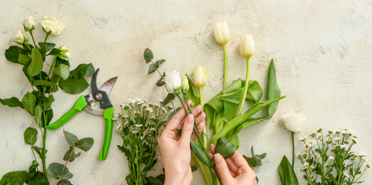 white and green flowers on a bench being prepped for arranging.