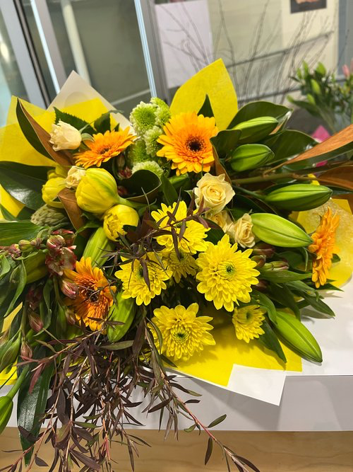 Bright Sunshine floral bouquet made with a variety of vibrant yellow flowers with foliage, wrapped in matching paper. Perfect for Mother&
