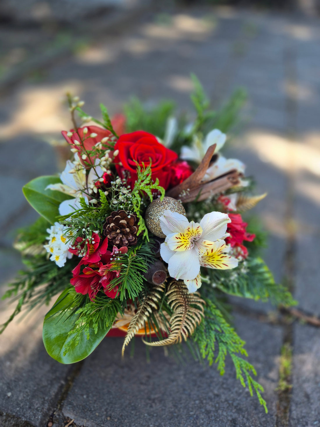 Christmas Posie Box made with red, green ang white flowers and foliage, adorned with festive pinecones, dried orange and Christmas decorations.