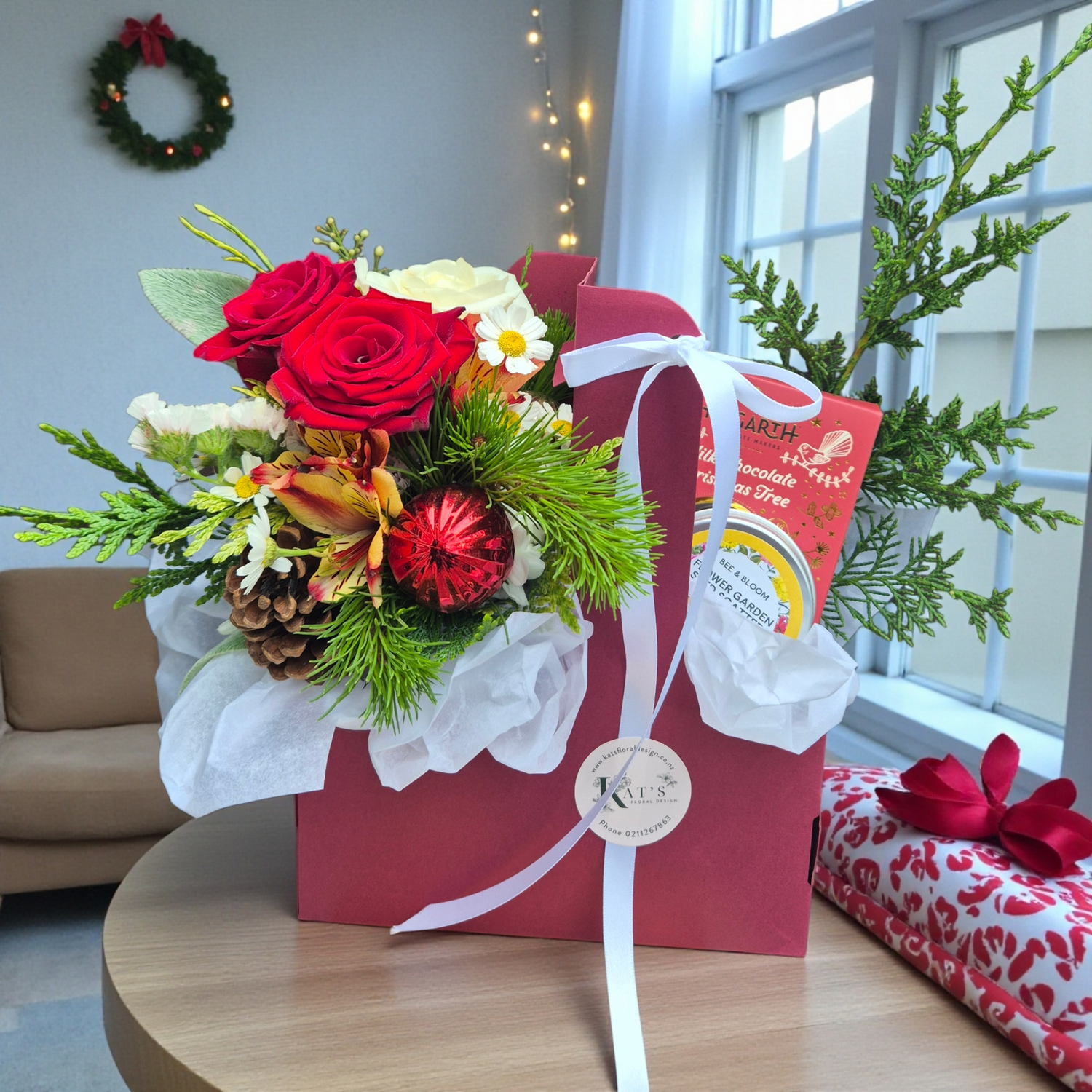 Merry Moments Gift Tray with festive flower bouquet, complete with chocolate and flower seed mix, presented in a red gift tray with tissue paper.