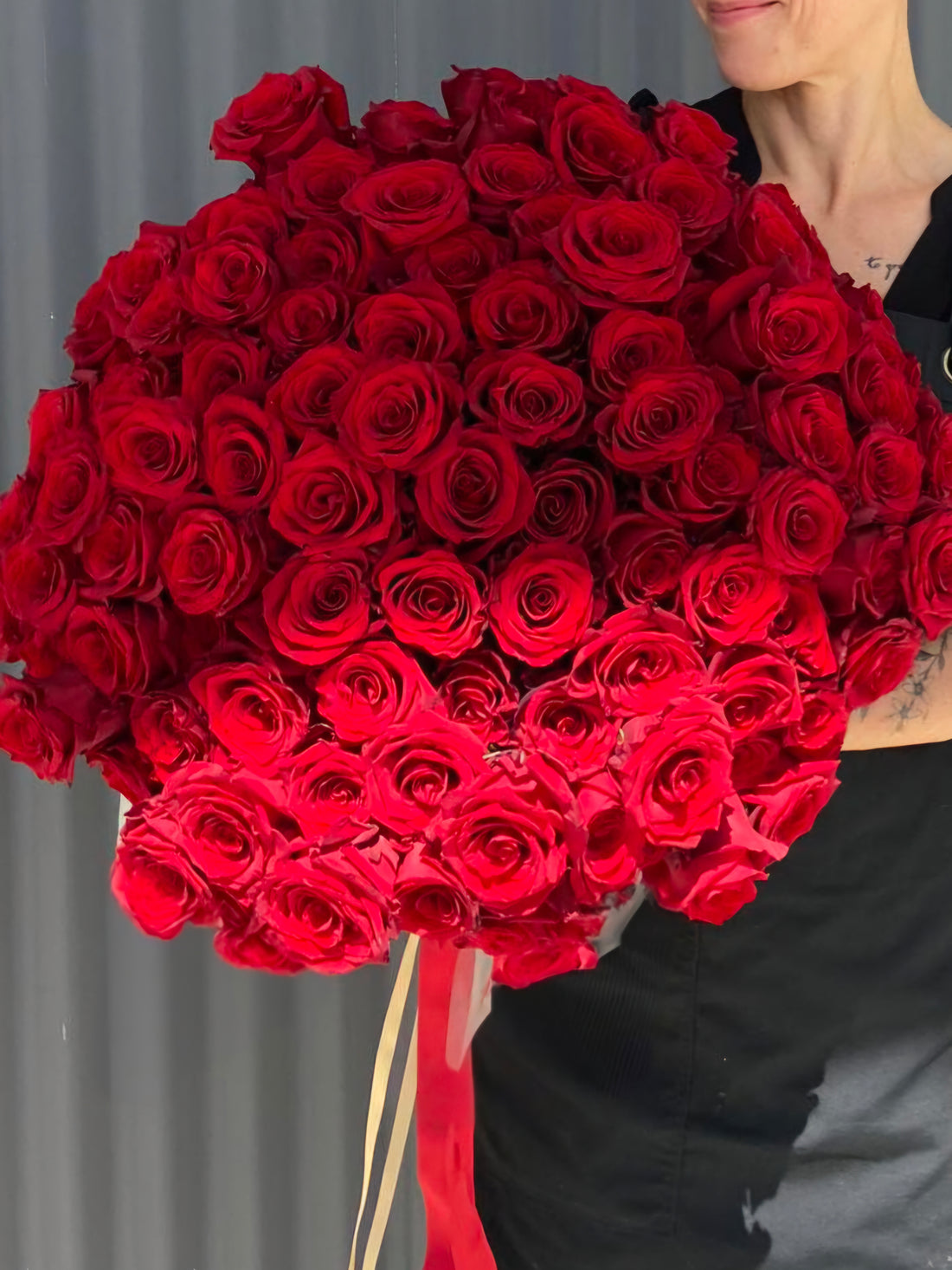 100 red rose bouquet tied with red and gold ribbon.