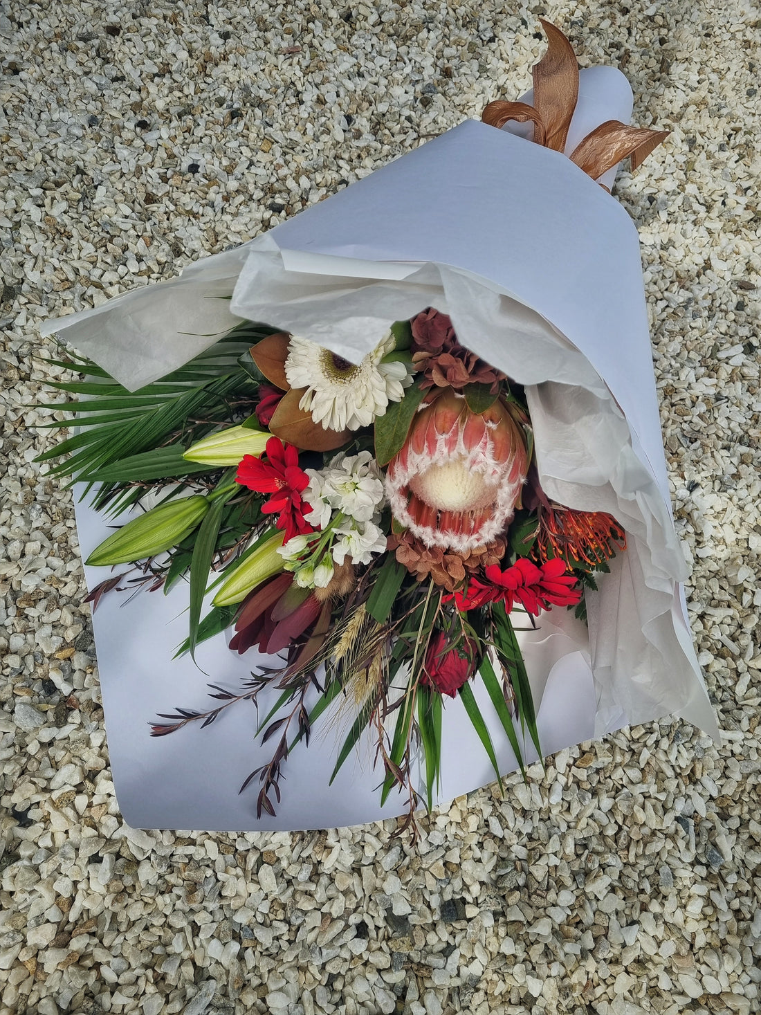 Rustic Bouquet with soft warm-toned flowers with foliage, wrapped in white tissue paper.