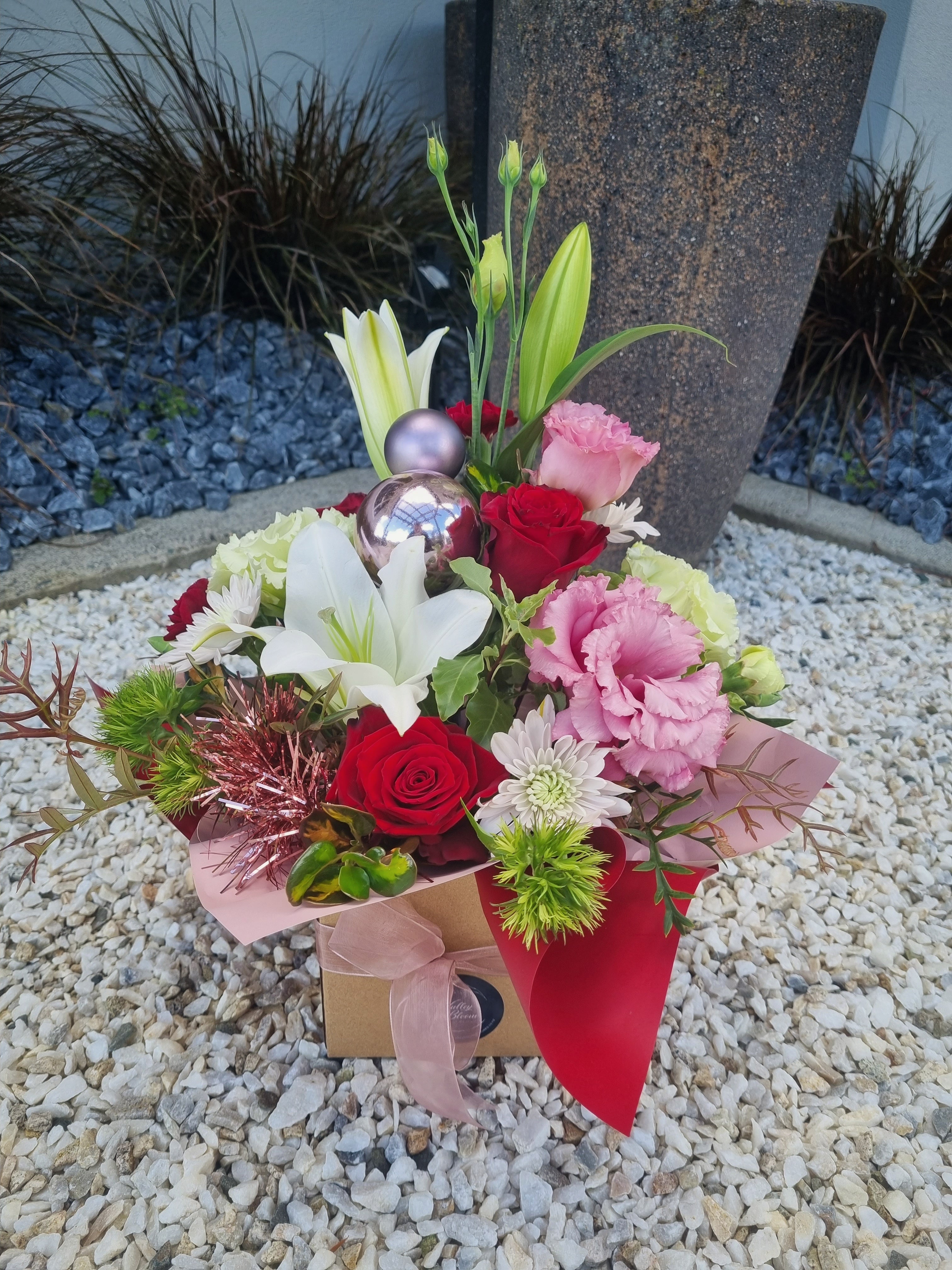 Merry Xmas Posy Box made with a variety of white, red and pink flowers complete with Christmas decorations, presented in a cardboard box with matching festive paper and ribbon.