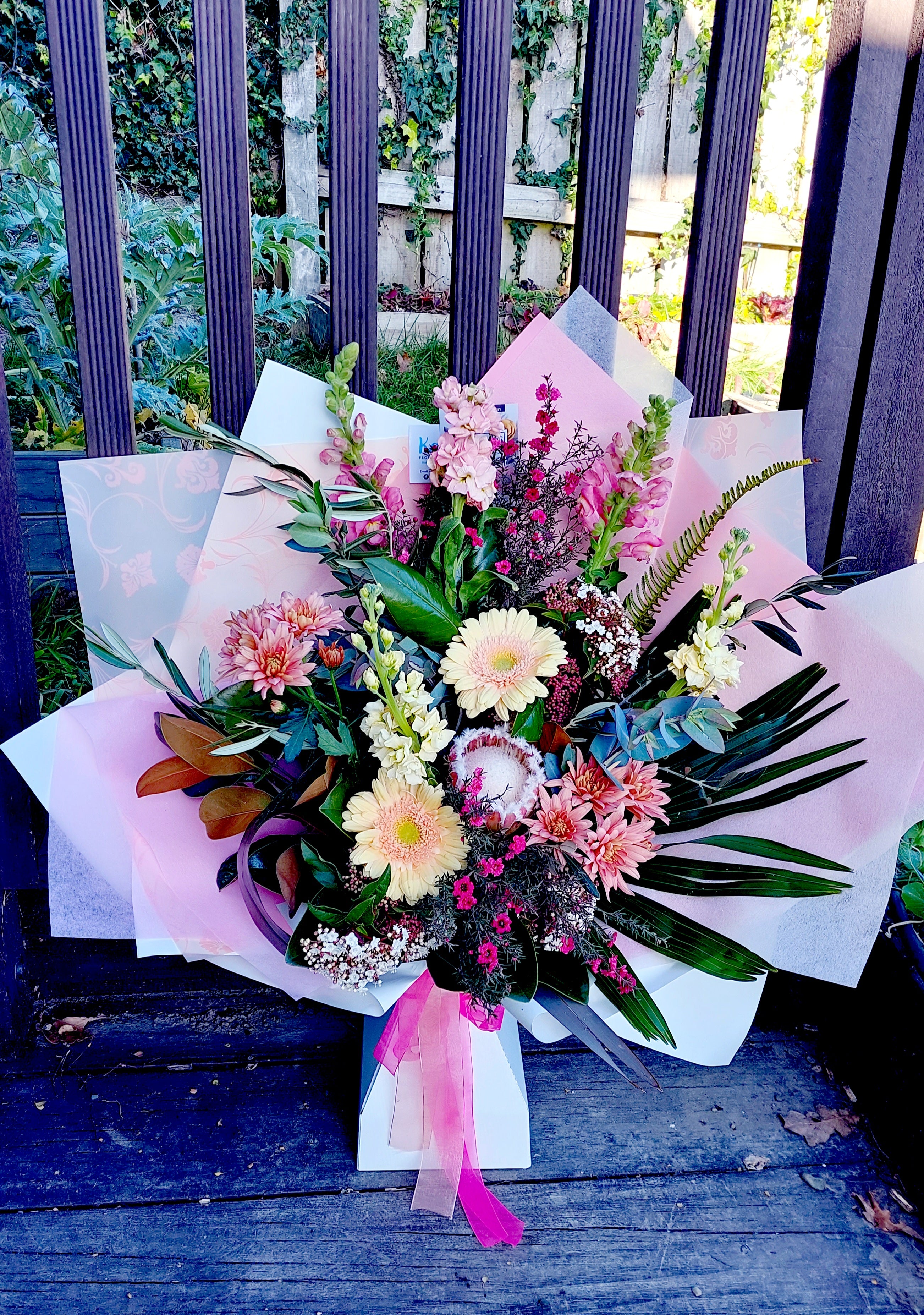 Seasonal Large Bouquet - Florist Choice by Kat's Floral Design. A peach-pink flower arrangement wrapped in pink tissue paper.