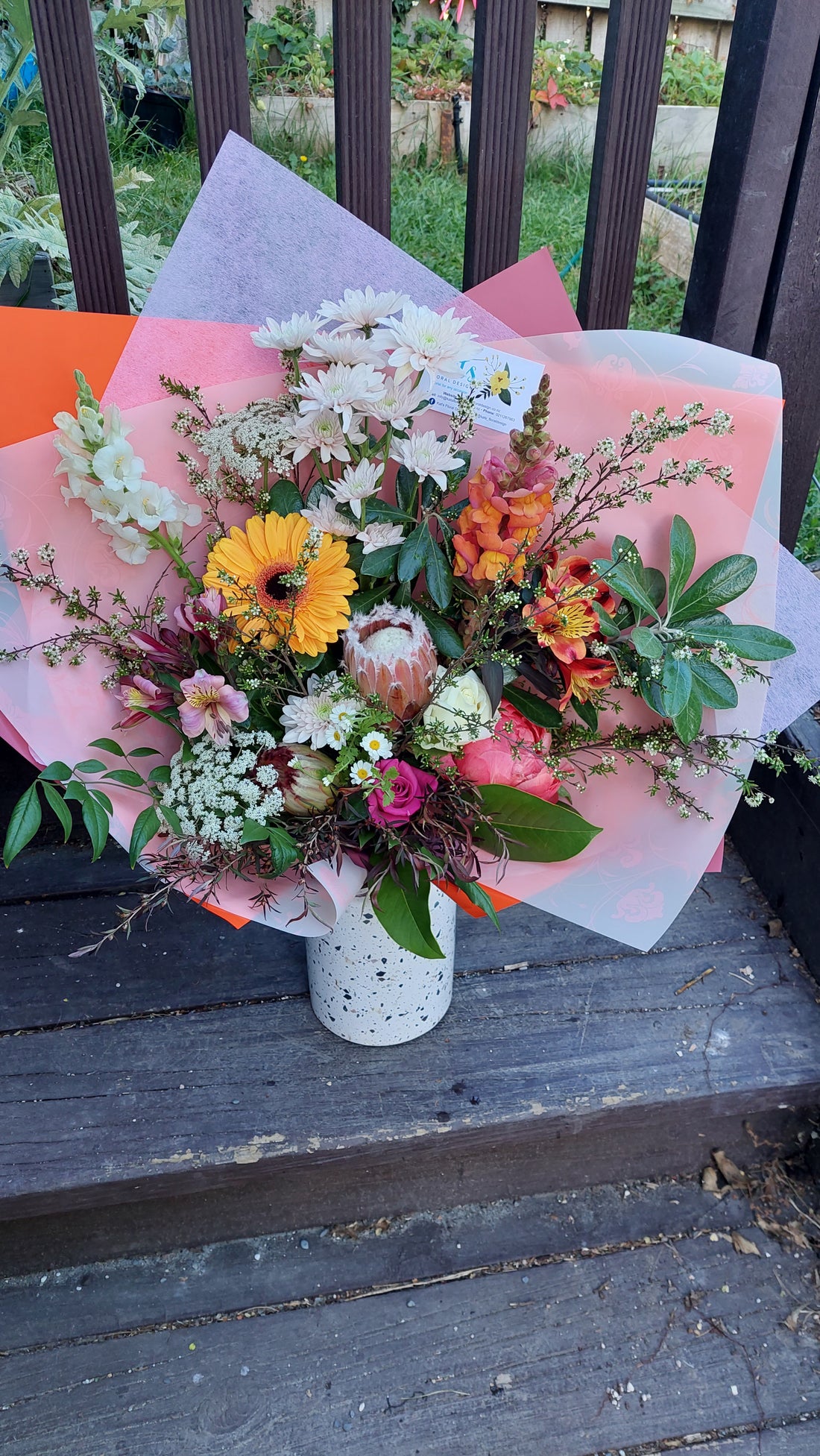 Seasonal Medium Bouquet - Florist Choice with white and yellow flowers wrapped in pink and white tissue paper.