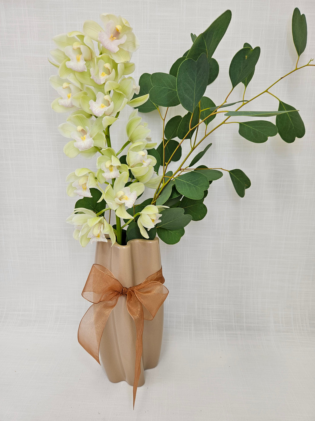Exceptionally Her bouquet presented in a twirly pink Ceramic Vase wrapped with a champagne bow. A single stem of miniature orchid.