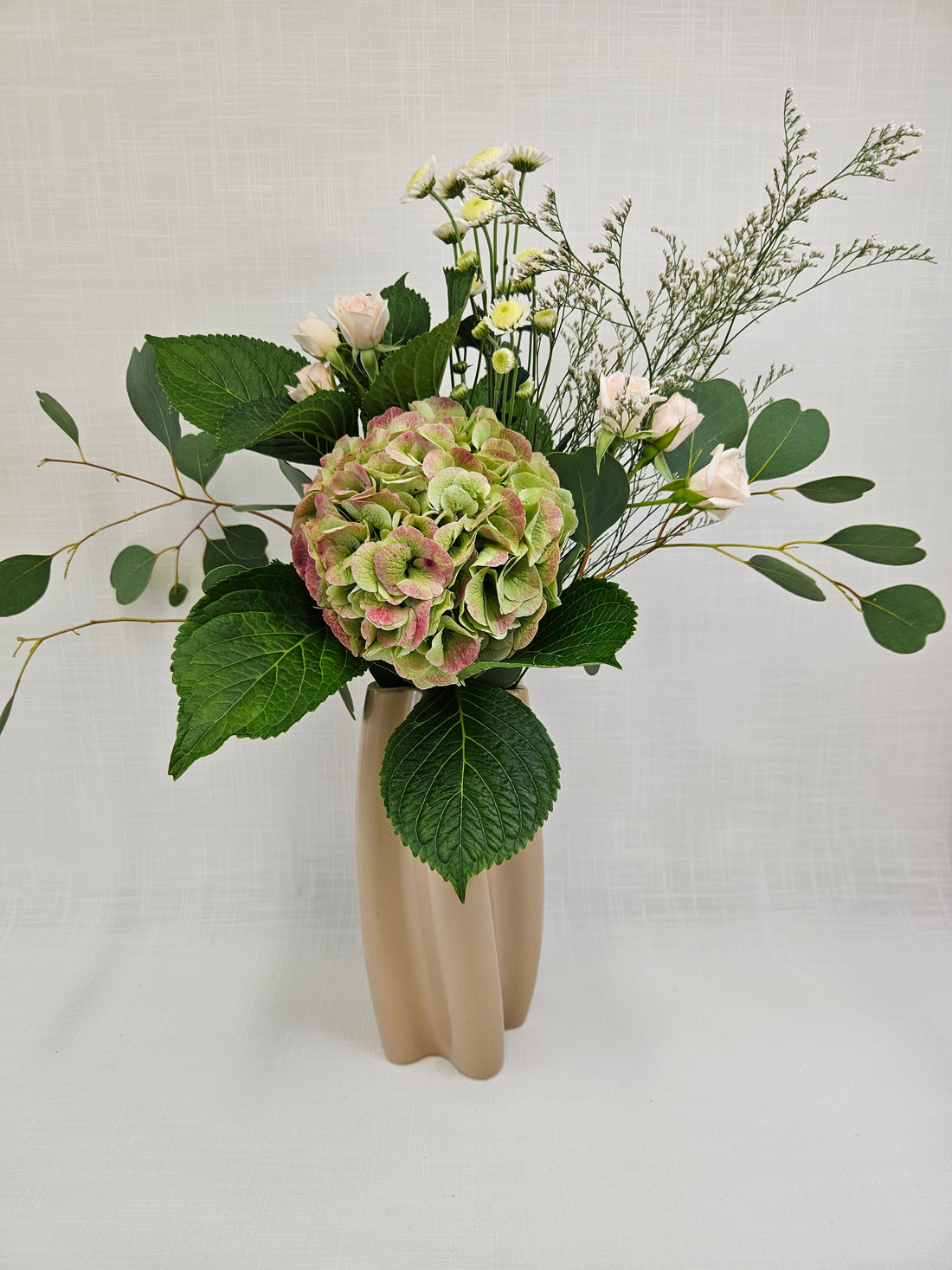 Best Mum Bouquet arranged in a twirly pink Ceramic Vase.. A floral arrangement made from roses, hydrangeas and more.
