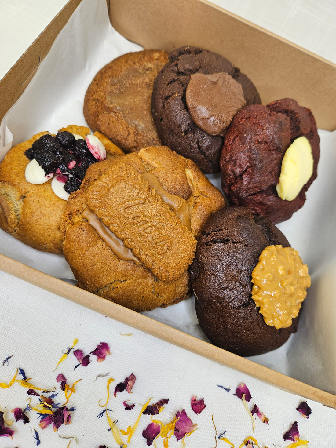 A box of 6 large gourmet biscuits in a variety of delicious flavours, packaged in a cardboard carry box.