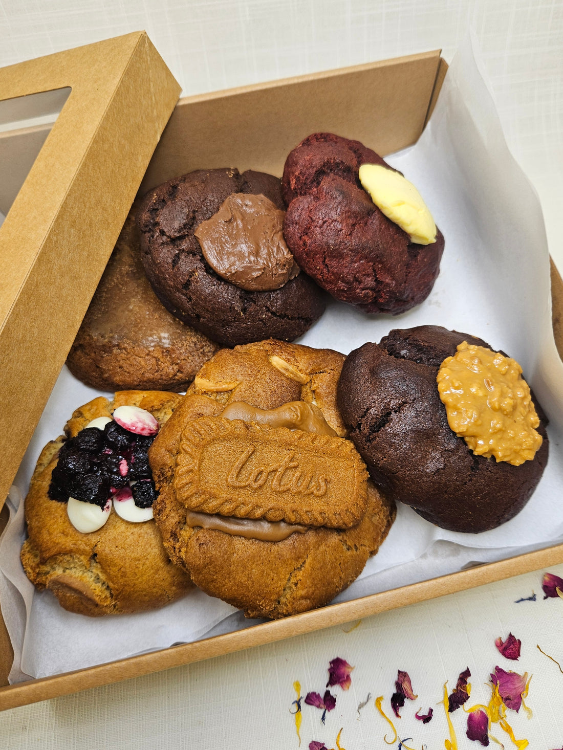 A box of 6 large gourmet biscuits in a variety of delicious flavours, packaged in a cardboard carry box.