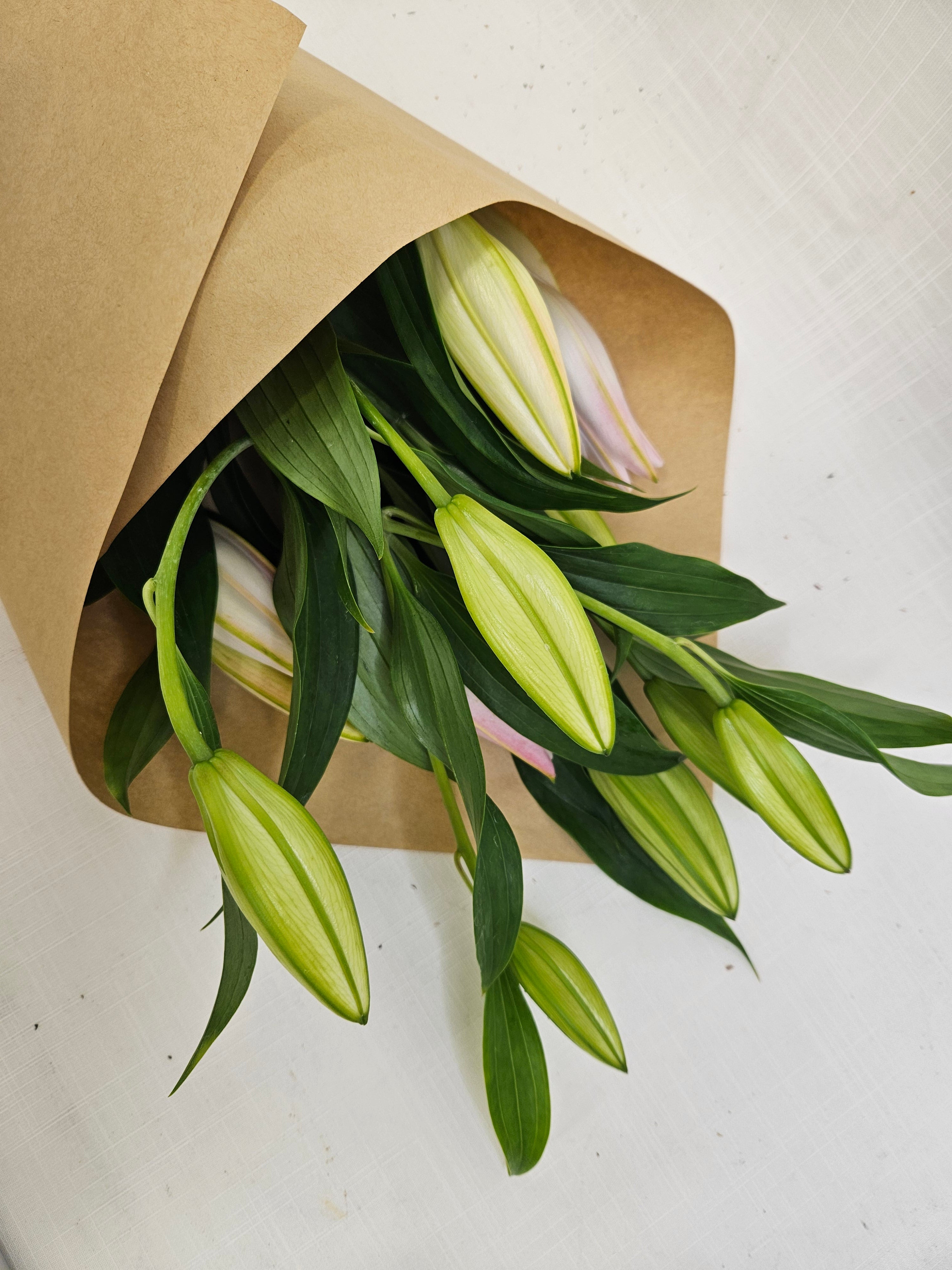 A bunch of Market Lillies in pink and white colours, wrapped in kraft paper.