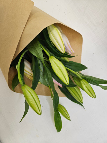 A bunch of Market Lillies in pink and white colours, wrapped in kraft paper.