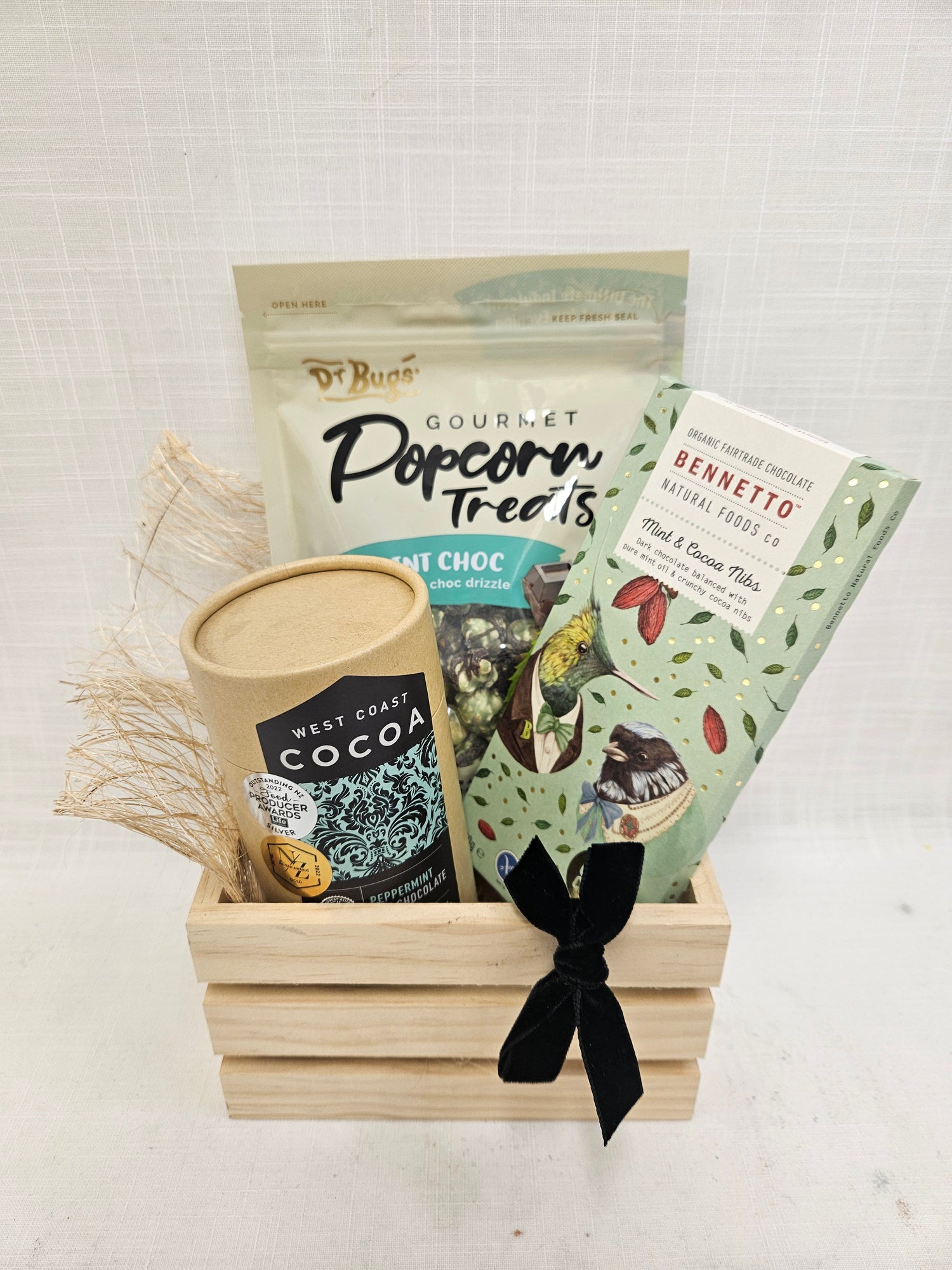 Mint Man gift basket containing Dr Bugs Mint Choc Popcorn, Bennetto Mint &amp; Cacao Nib Chocolate and West Coast Peppermint Cocoa, presented in a wooden crate tied with a black ribbon.