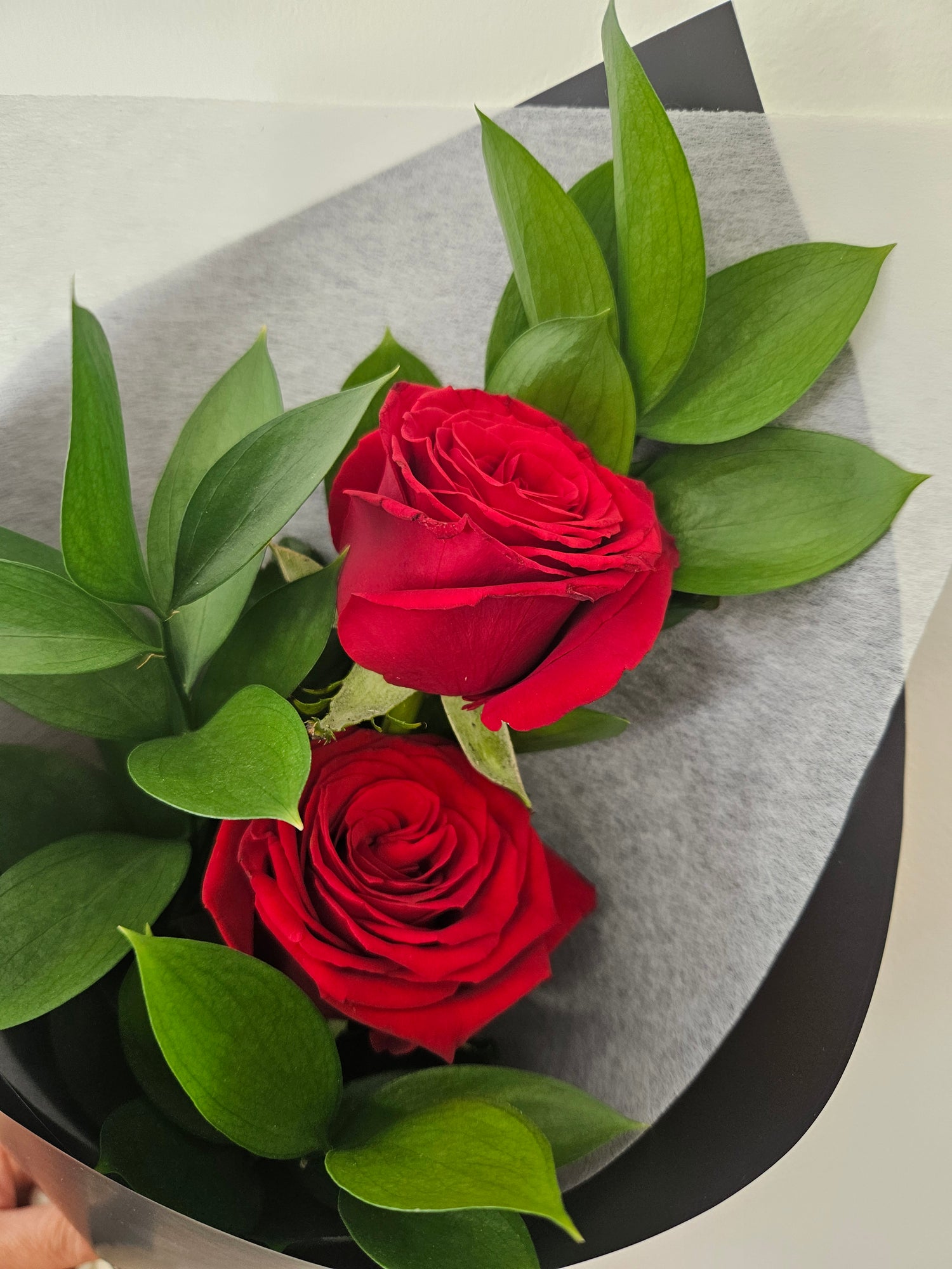 Two of a Kind red rose bouquet wrapped in white and black paper and fabric, tied with a ribbon that reads &