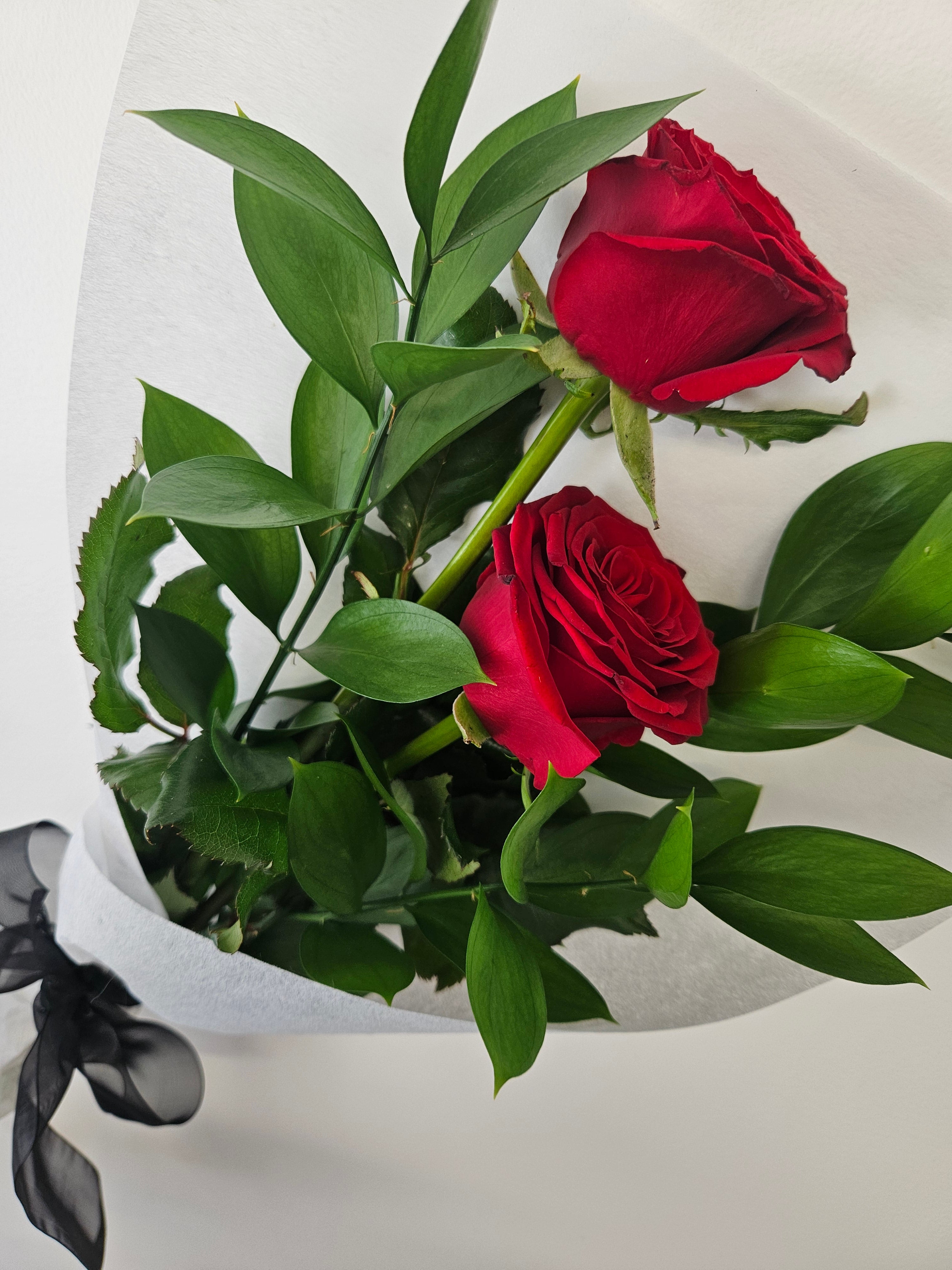 Two of a Kind red rose bouquet wrapped in white and black paper and fabric, tied with a ribbon that reads &