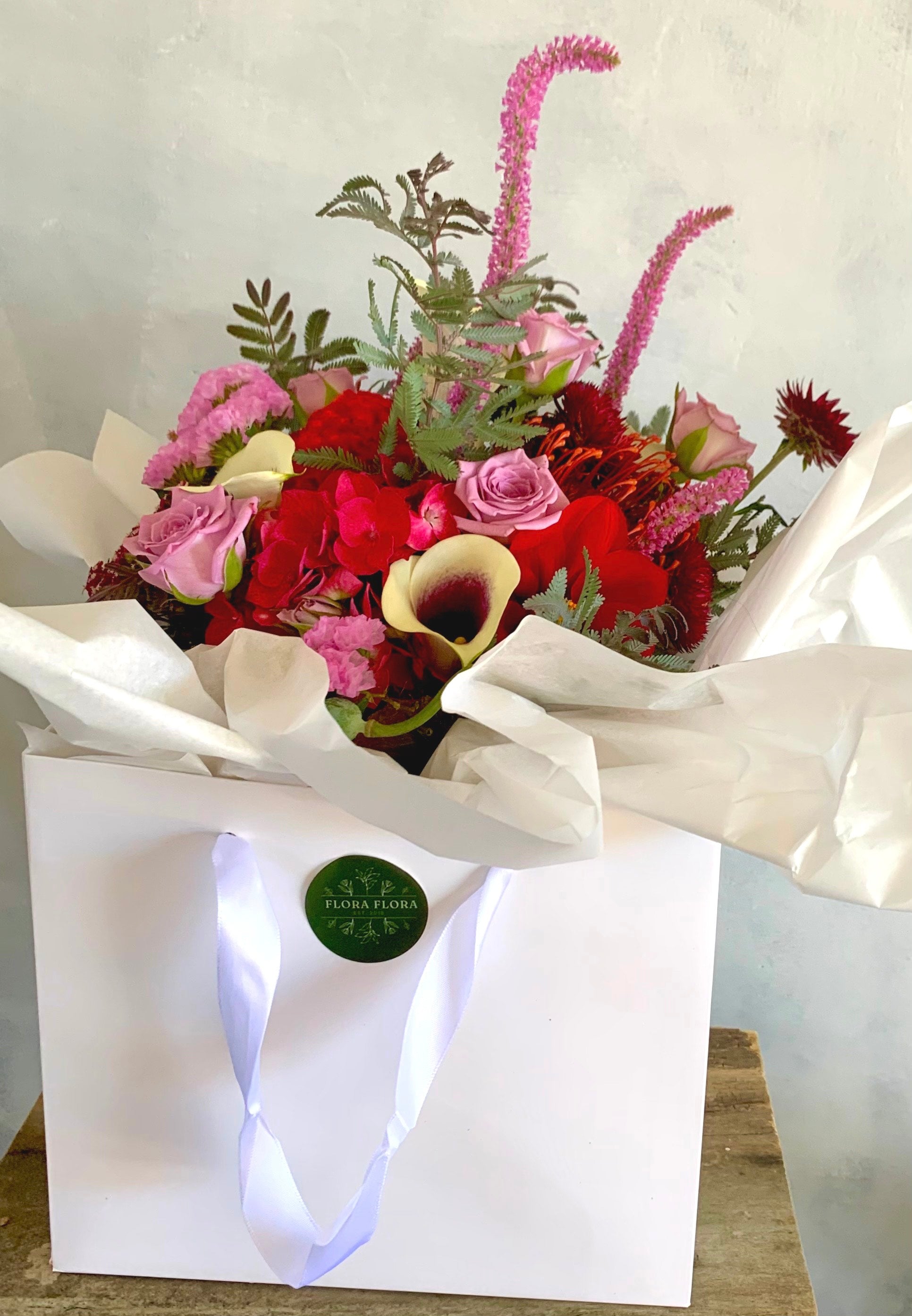 Christmas Posie made with rich red, purple and pink flowers and foliage, presented in a white gift box.