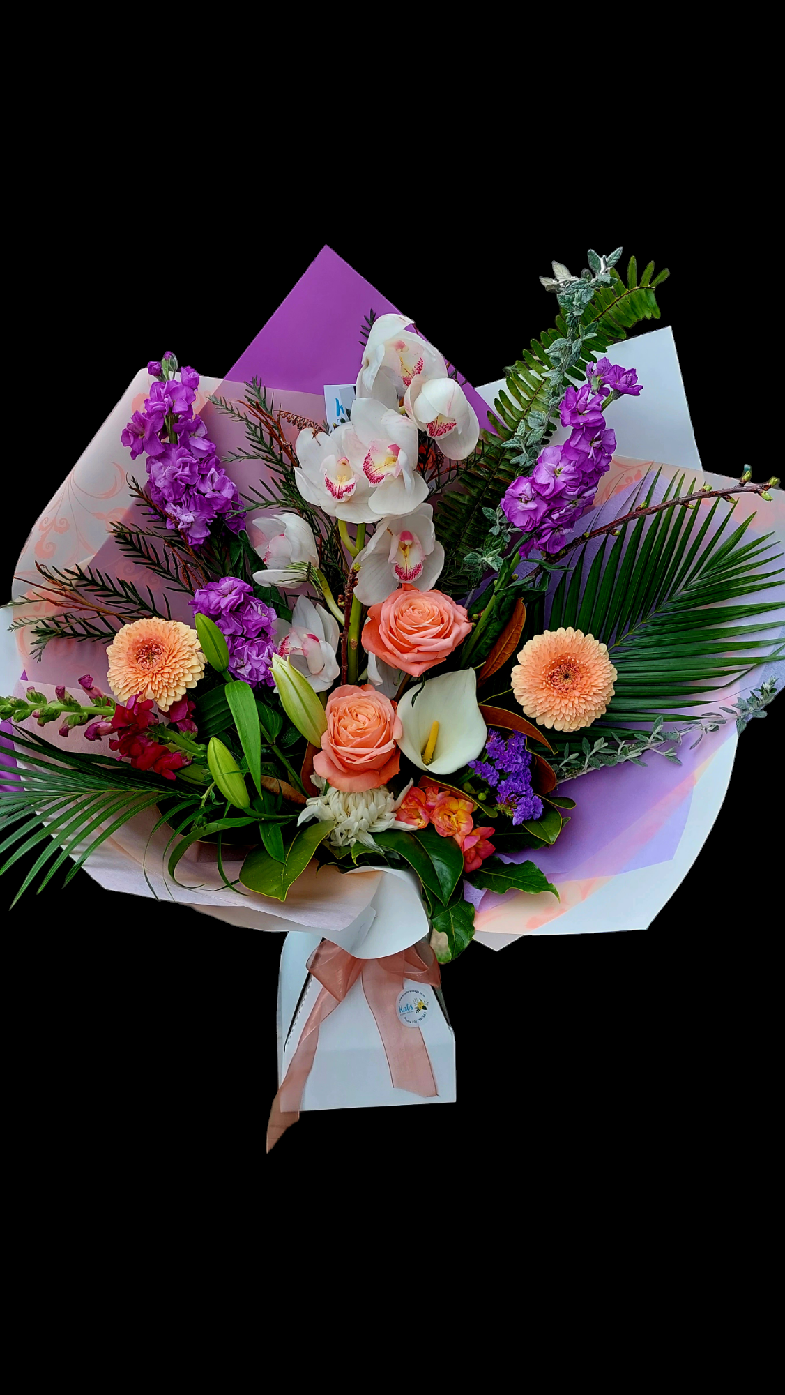 Seasonal Bouquet - Florist Choice with orange/purple flowers and green foliage, wrapped in peach and purple tissue paper.