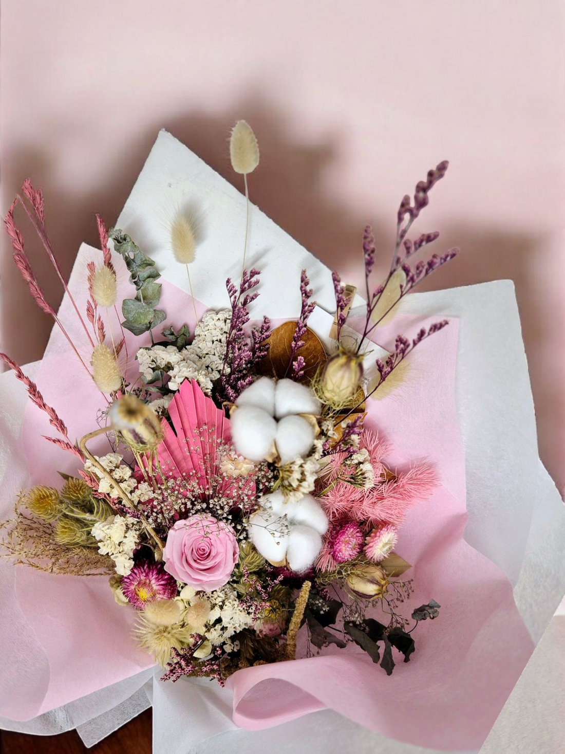 Blush & Bloom dried floral bouquet, made with pink and white flowers and neutral foliage, wrapped in pink and white tissue paper.