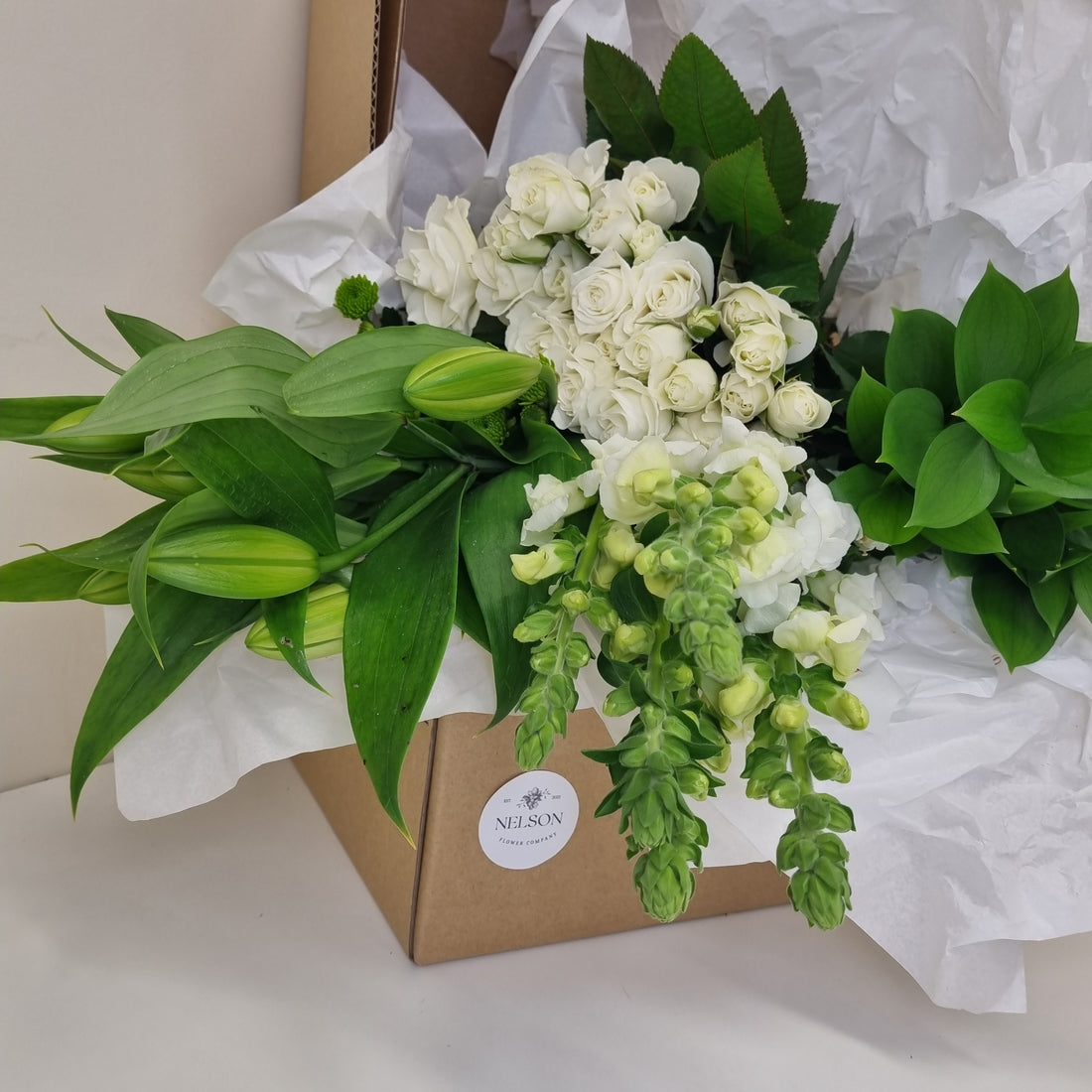 Elegant &amp; Understated Fresh Flower Box, with greenery in a cardboard box with white tissue paper.