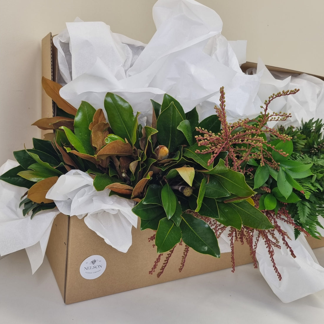 Fresh Greenery box with various leaves and other foliage in a cardboard box with white tissue paper.