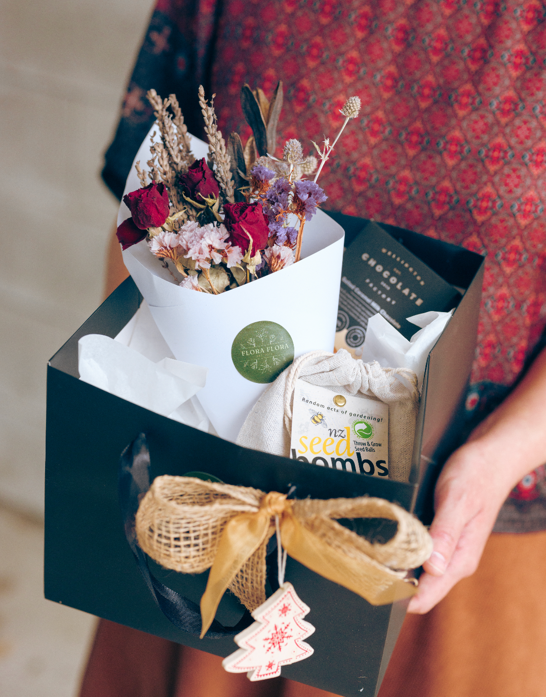 Eco Christmas Gift Box comprised of a medium dried floral posy wrapped in white paper, a Seed Bomb for your garden, and a bar of delicious chocolate.