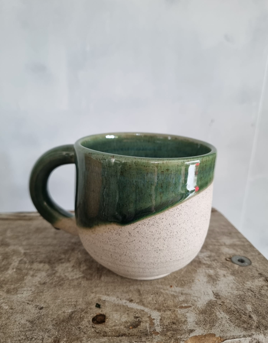A beautiful handmade mug with half-dipped dark green glaze, by Francis Pottery, as part of the Orchid Giftbox by Flora Flora.