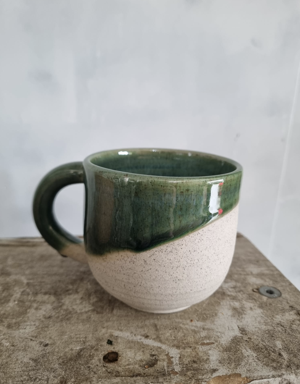 A beautiful handmade mug with half-dipped dark green glaze, by Francis Pottery, as part of the Orchid Giftbox by Flora Flora.