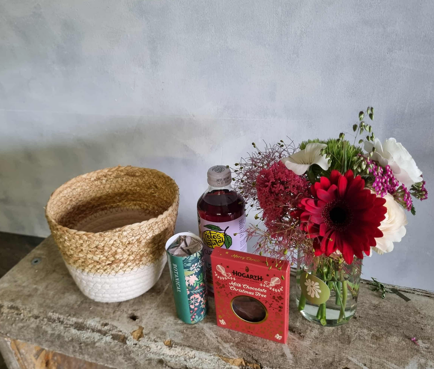 Feeling Festive gift basket complete with floral posie in festive colours, beverage, chocolate and tea lights, presented in a cute basket.