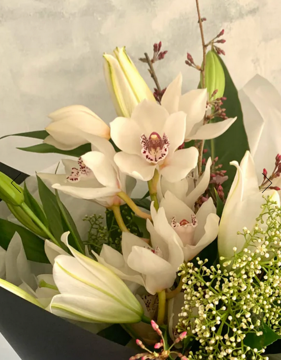 Sympathy Bouquet made with white flowers and foliage, wrapped in matching paper.
