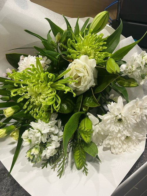 Minty Fresh bouquet made with a variety of green and white flowers and foliage, wrapped in white tissue paper. Perfect for Mother's Day!