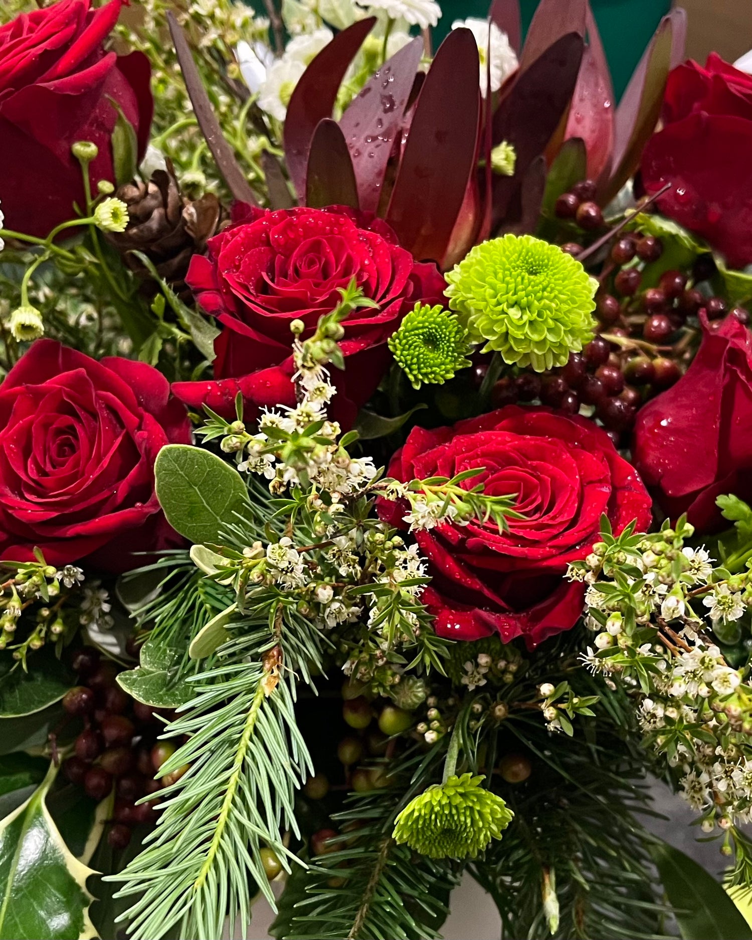 Christmas Posy Box Arrangement made of festive red, white and green flowers and foliage.